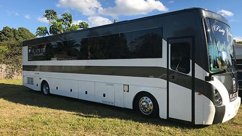 A large white bus parked in the grass.