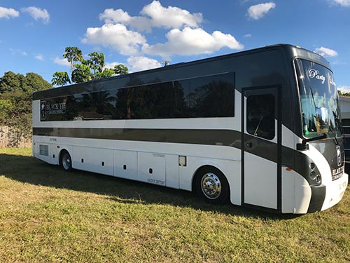 A large white bus parked in the grass.