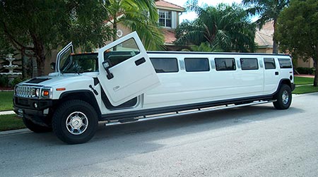 A white limo is parked on the side of the road.