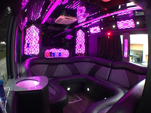 A party bus with purple lights and black leather seats.