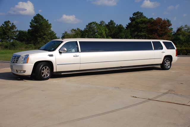 A white limo is parked in the gravel.