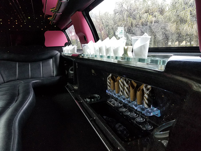 A pink and black limo with a table in the back