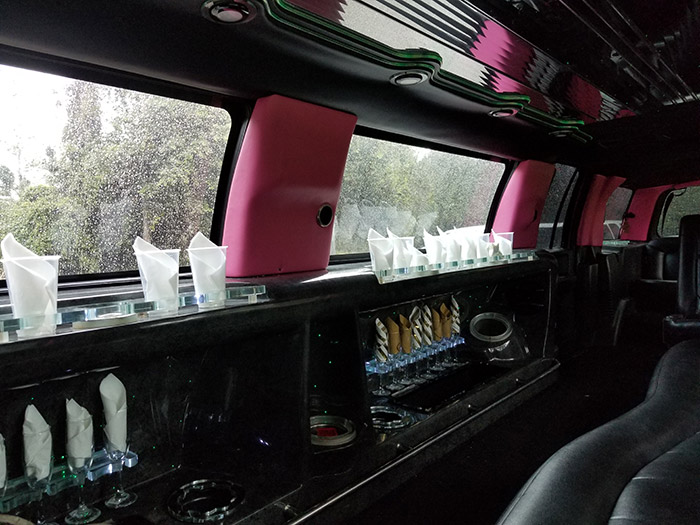 A bar with pink cups and bottles on the side.