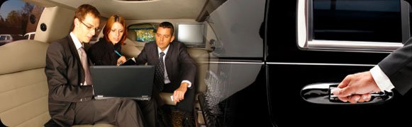 A man sitting in the back of a car with his laptop.