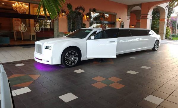 A white limo is parked in the lobby of a hotel.