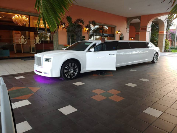 A white limo is parked in the lobby of a hotel.